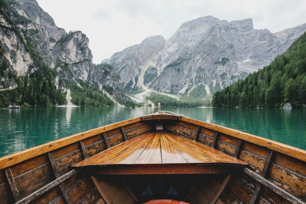A wooden boat on the turquoise water of Lago di Braies with mountain peaks